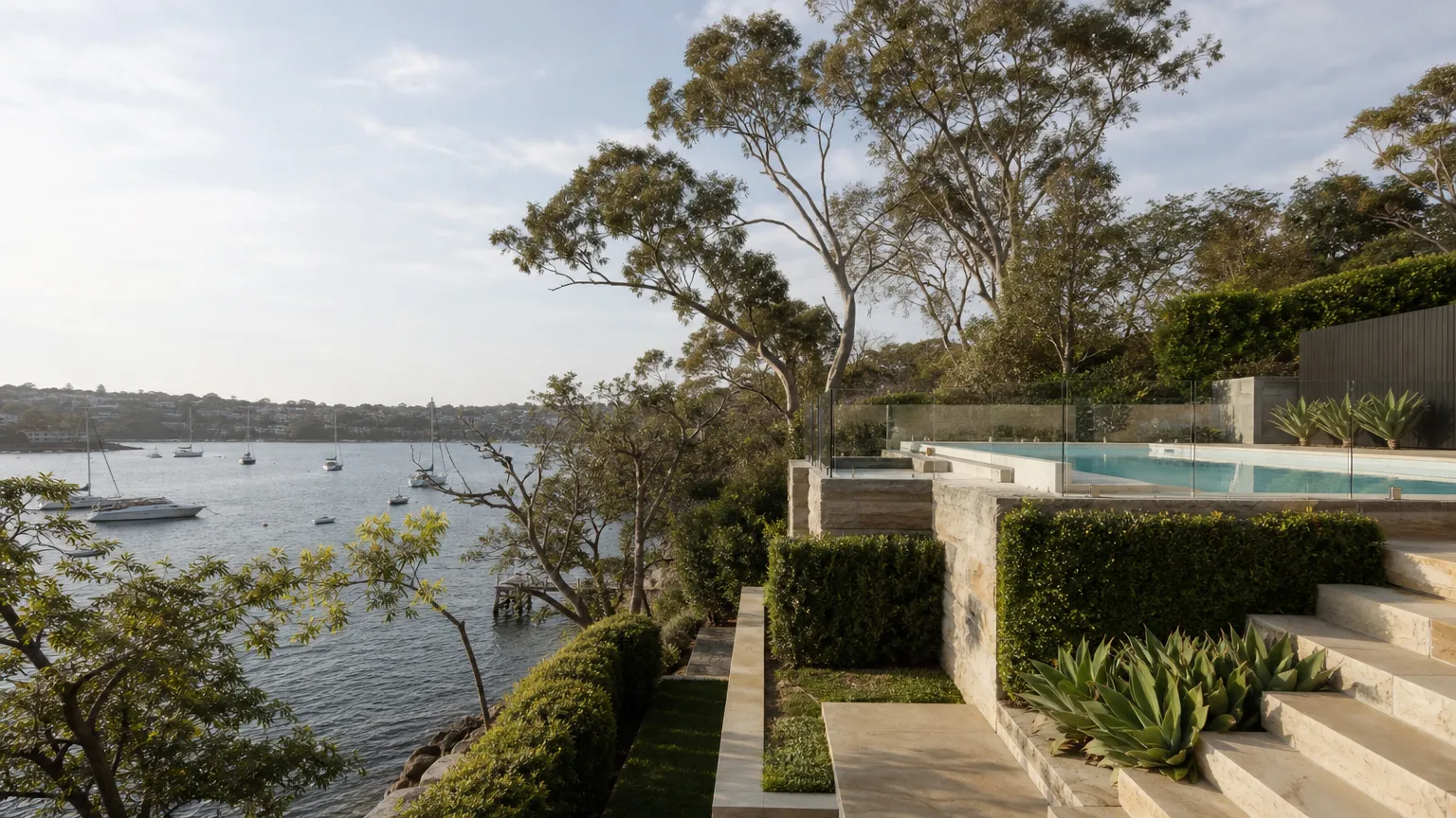a frameless glass pool fence on a stepped garden terrace looking out over a harbour